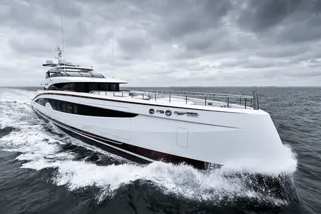 Sparta - A sleek white luxury yacht cruising through the water with a cloudy sky overhead